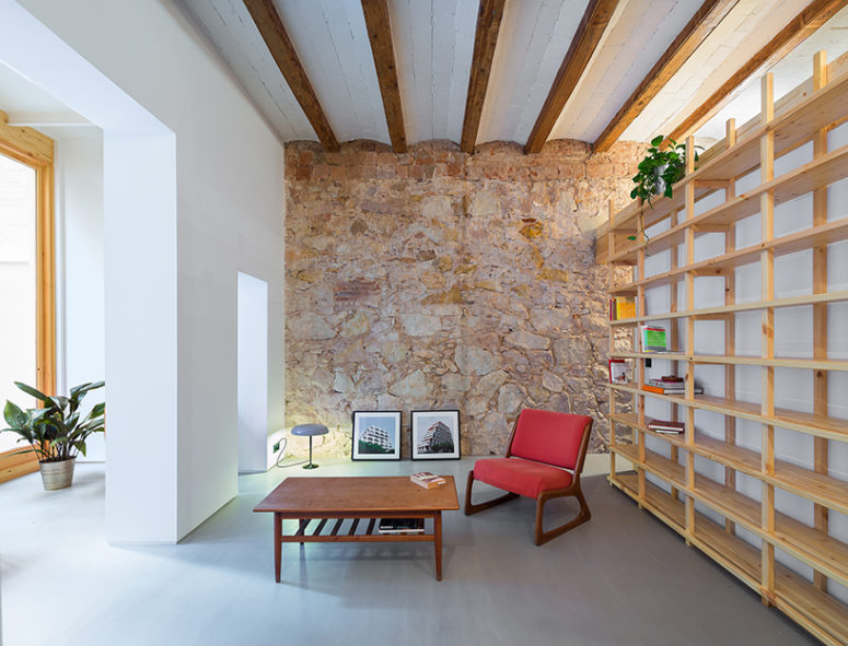 stone accent wall The living room features a rough stone wall and wooden beams on the ceiling plus comfy furniture and a couple of artworks