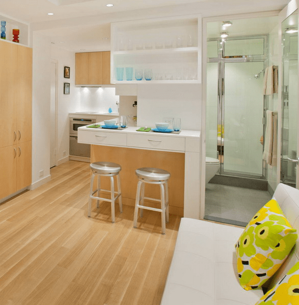 The small kitchen features white countertops and lots of drawers for storage, they hide the bathroom partly