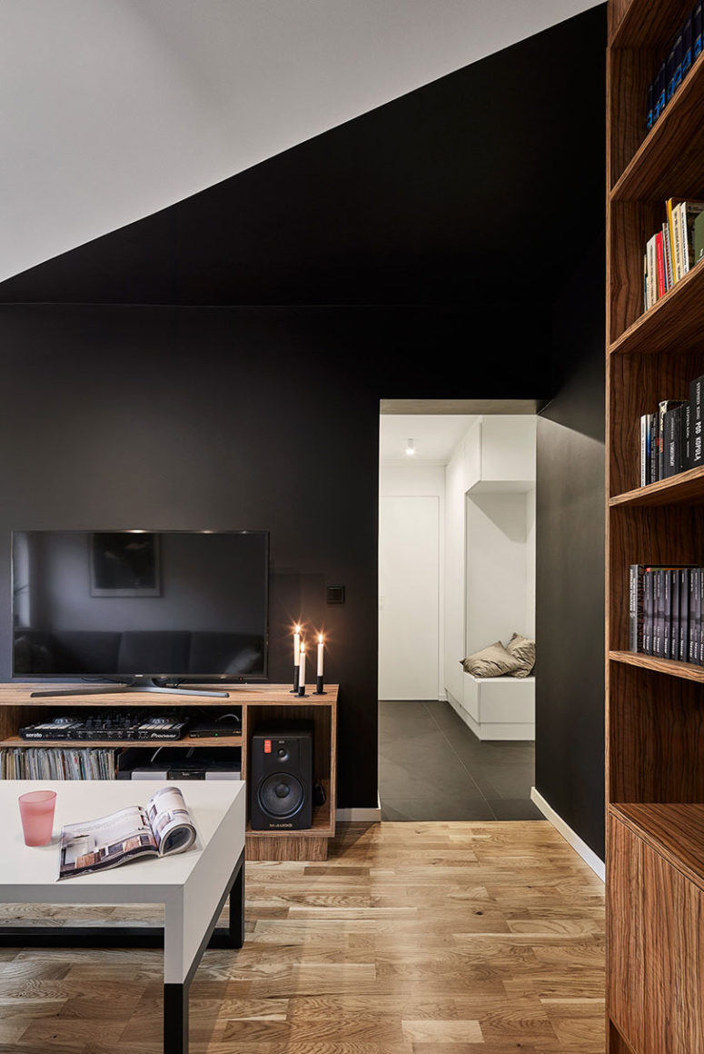 The statement black walls are softened with warm-colored wooden furniture