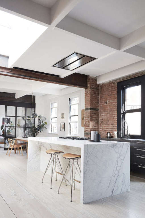 The kitchen and dining space are united into one open layout that is separated visually with a ceiling beam and different wall cover