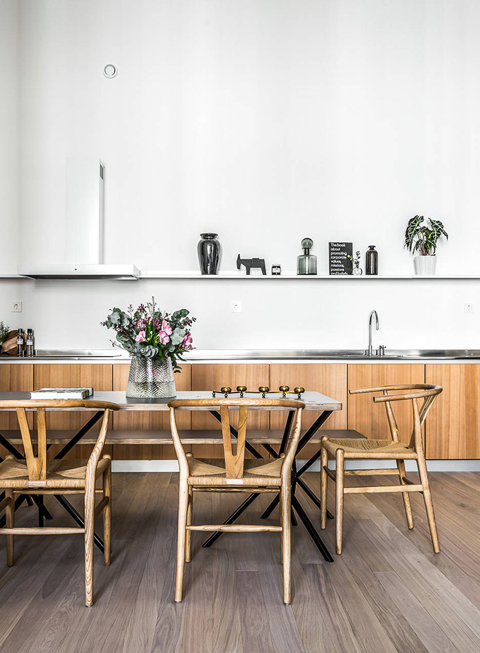 The kitchen comes along a living room wall and features light-colored wooden cabinets and an long shelf