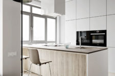 04 The kitchen features light-colored cabinets with no handles, a large kitchen island that doubles as a dining table