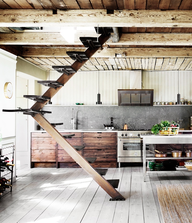 The kitchen has dark stained wooden cabinets and open shelving, a stainless steel kitchen island works as a space divider