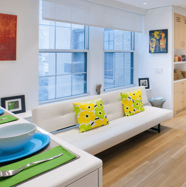 The living room has a white sofa and a large TV, it's spruced up with colors