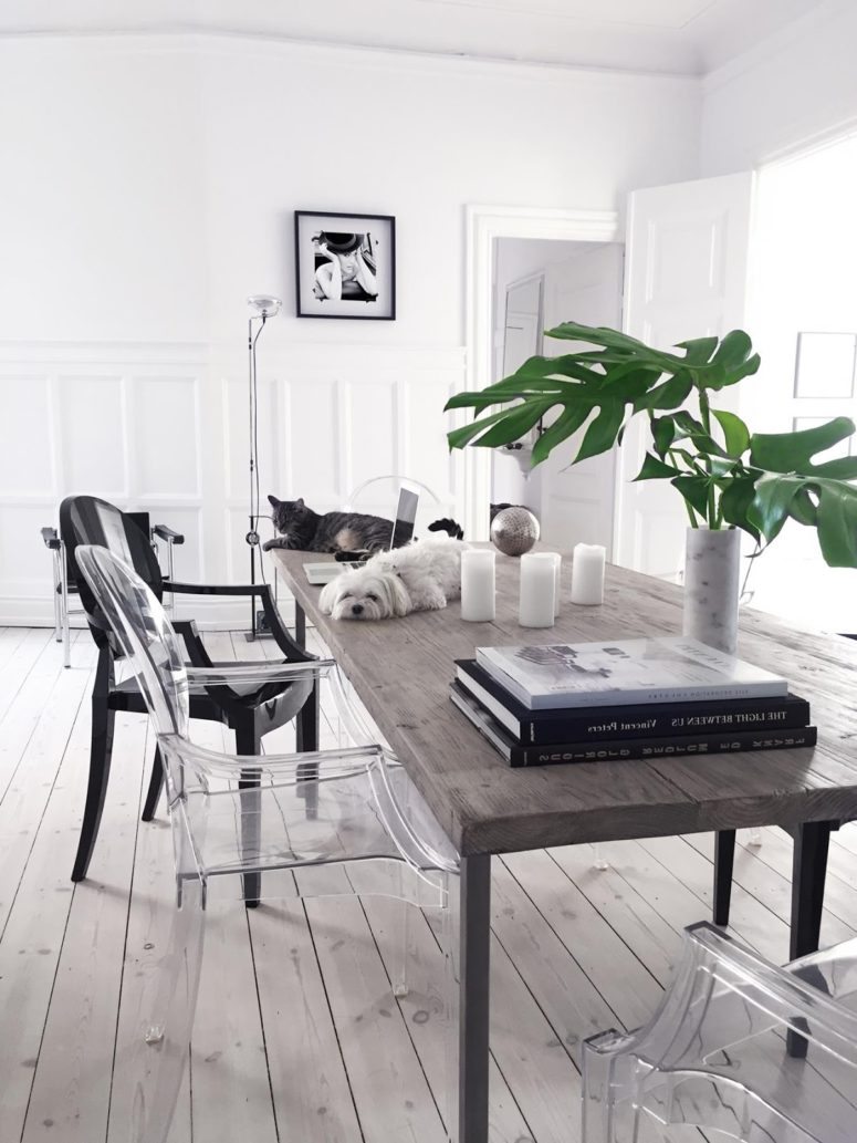 This is a dining room with a rustic wooden table and mismatching modern chairs of acryl and plastic for a contrast