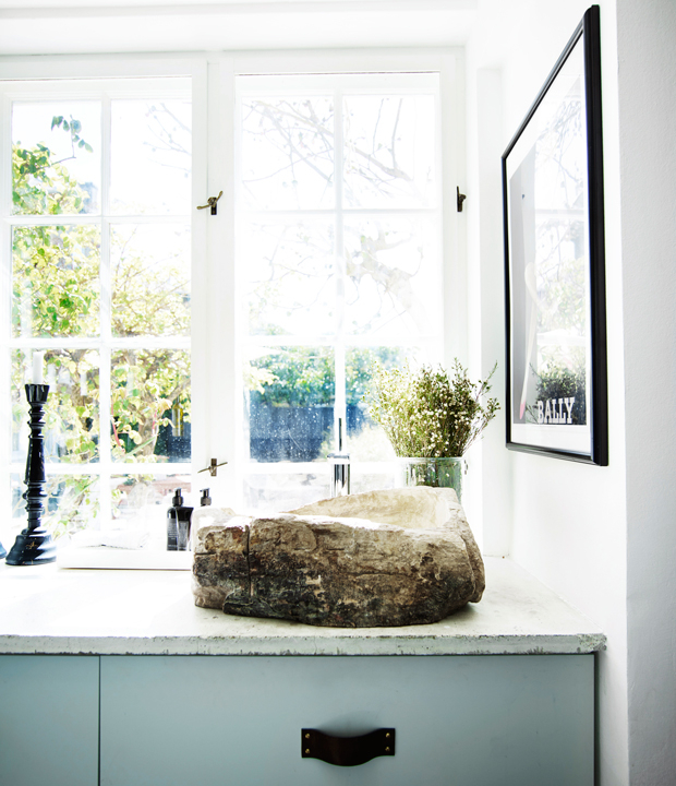 The bathroom has framed windows and a stunning rough wood sink contrasting with modern surroundings