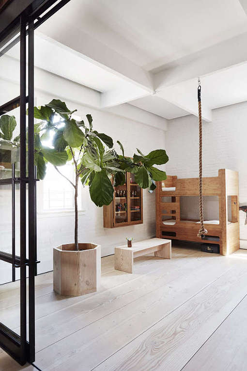 The kid's space continues the loft decor style with white brick walls, simple wooden furniture and a framed glass door