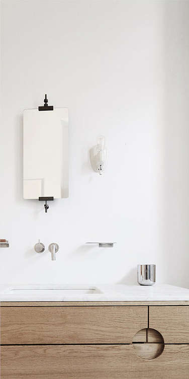 The bathroom shows off an exposed brick wall, a wooden vanity and a minimalist tub