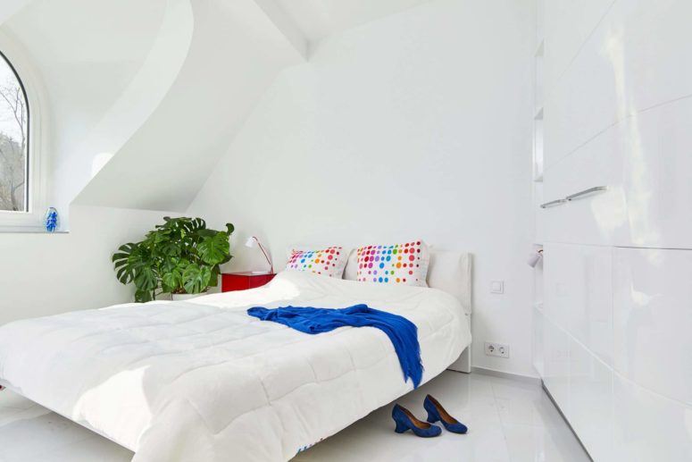 The master bedroom is all-white, with just a red nightstand and colors may be added with textiles