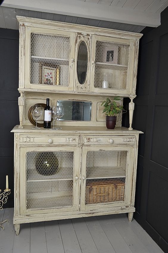 a warm pastel cupboard with chicken wire in compartment doors to see the objects better