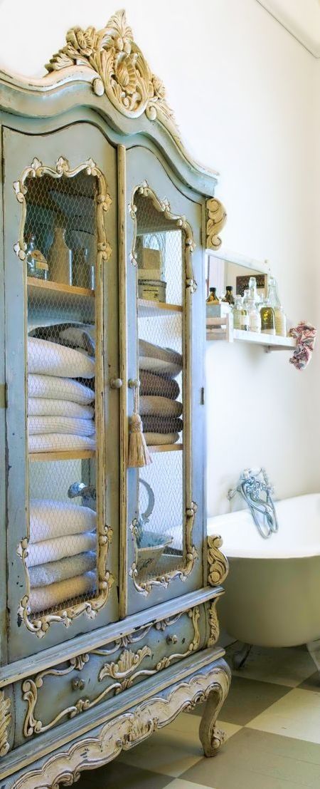 a vintage blue and cream cupboard with chicken wire for storing bathroom towels and other stuff