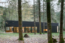 01 This gorgeous house with a black exterior is located in the forest, on a river and takes the advantage of the views