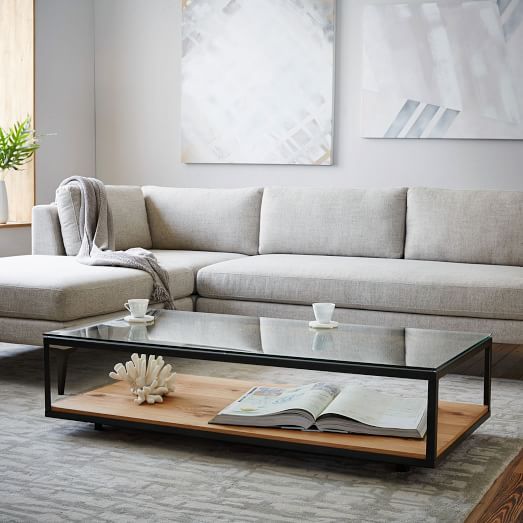 a black frame coffee table with a glass and a wooden top allows storage and looks cozy due to the wood texture