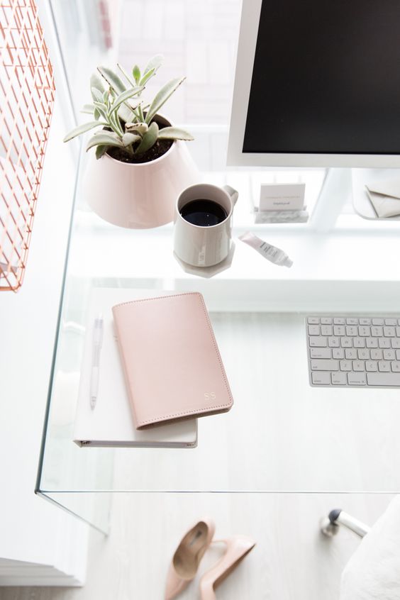 a clear glass desk in a white and blush home office looks ethereal