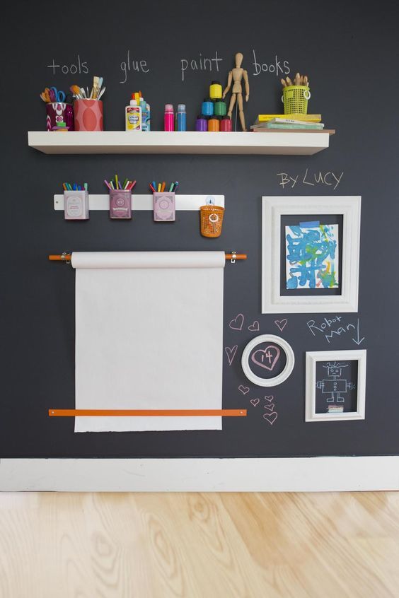 a drawing and painting space with a chalkboard wall, lots of pencils, paints, crayons and other stuff