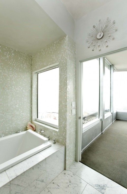 mother of pearl tiles cover the bathtub zone and make it stand out in a marble space