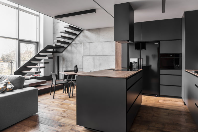 elegant kitchen design The kitchen is done in matte black and grey, large windows fill the open layout with light, and a linear staircase leaves some space for an eating zone