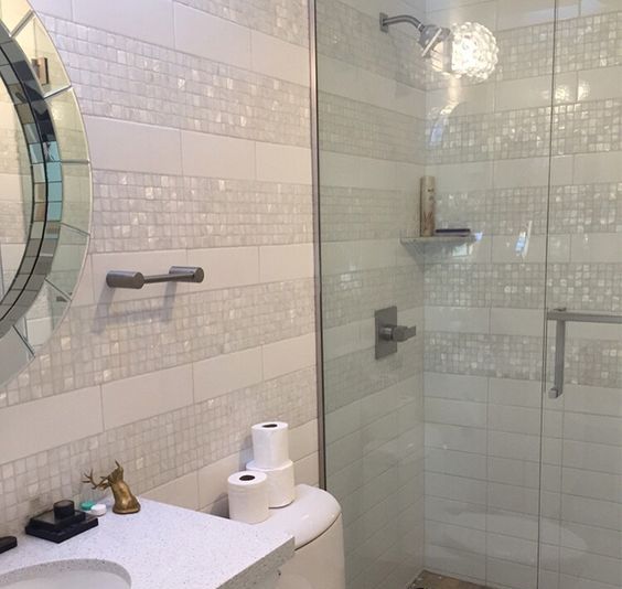 a glam creamy bathroom with mother of pearl accents and a mirror for an ambience