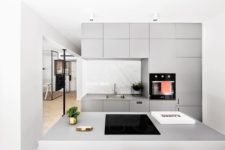 04 The kitchen is modern and minimalist, it’s done in light grey with marble inserts and some brass touches for elegance