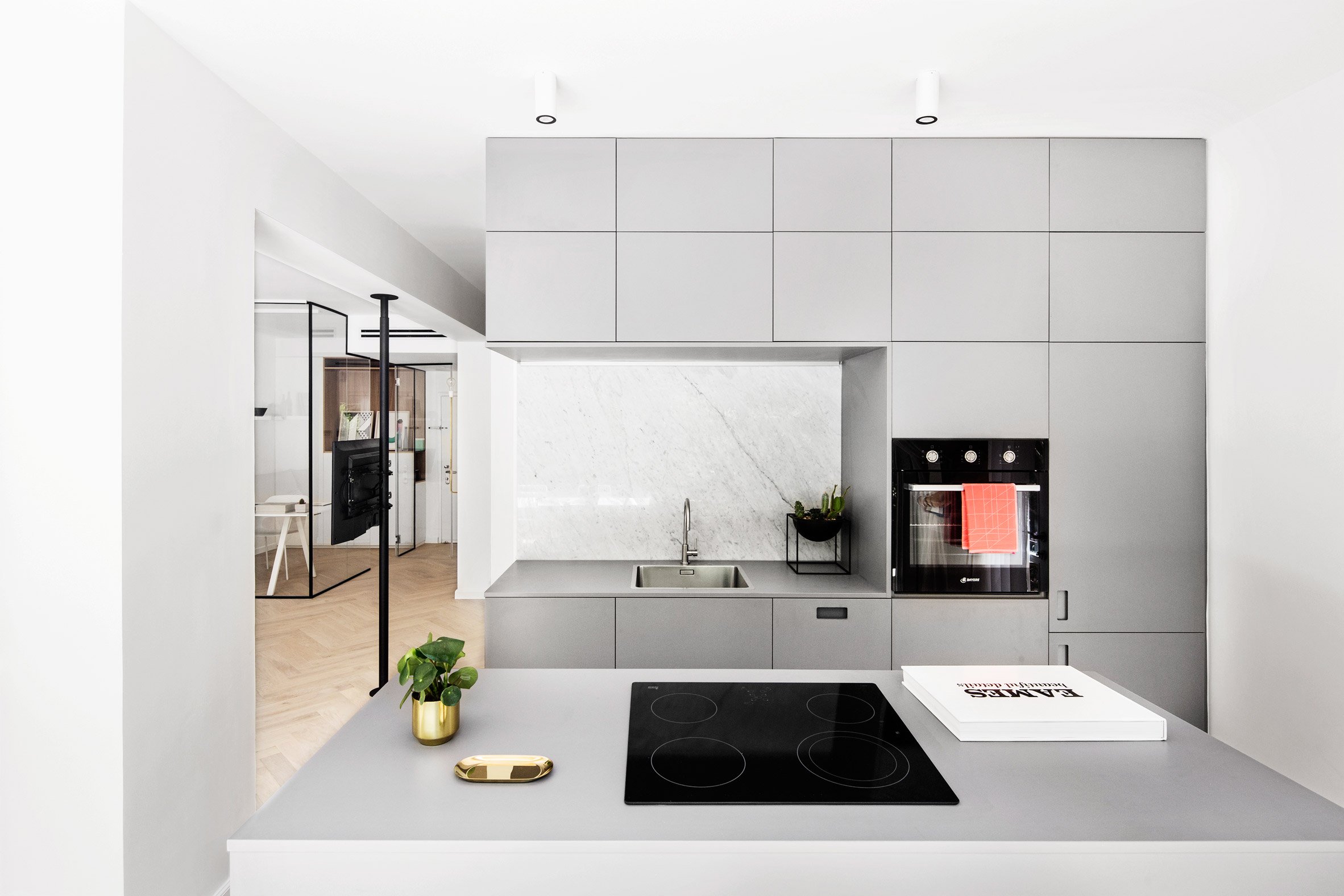 The kitchen is modern and minimalist, it's done in light grey with marble inserts and some brass touches for elegance