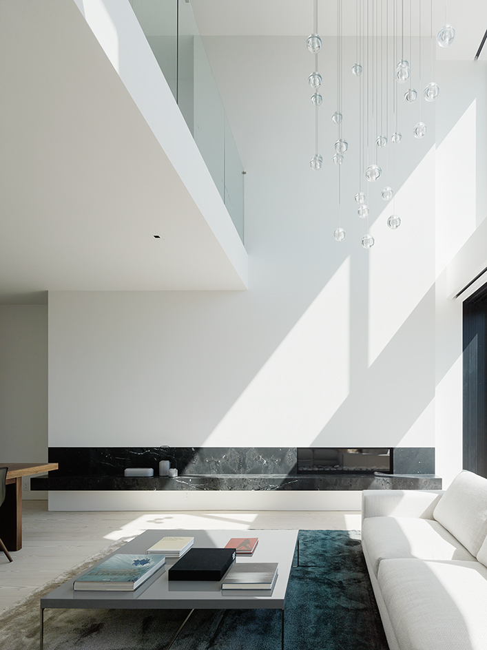 The living room is also white, with a black marble shelf and a gorgeous glass bubble chandelier to accentuate a high ceiling