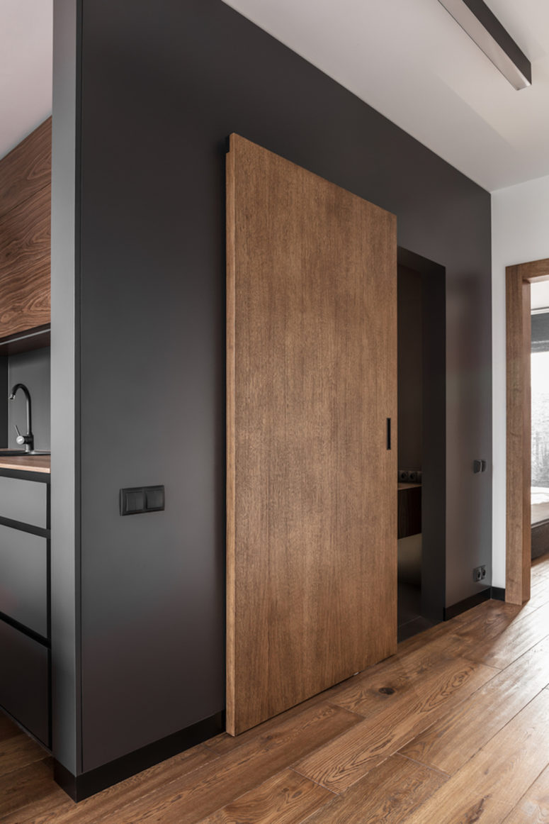 The large wooden door matches the floor and ensures cohesiveness throughout the apartment