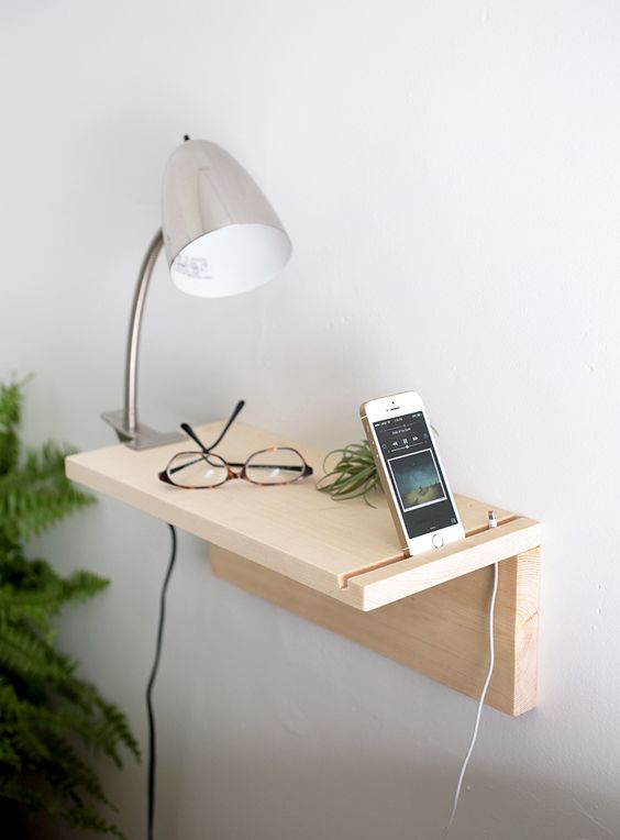 a minimalist wooden plank floating nightstand for holding just a couple of things and charging your phone