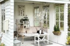 06 a shabby chic she shed in white, with a retro daybed, lanterns and some potted plants