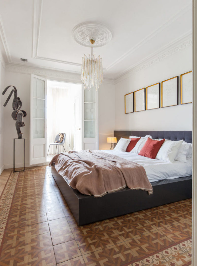 The second bedroom features a large bed, a glam chandelier and a sculpture in the corner