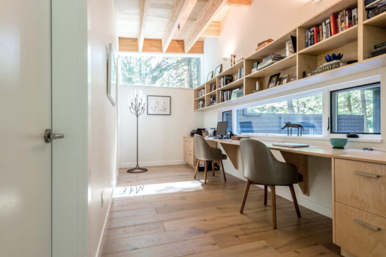 The shared working space features bookshelves over the desk and some windows instead of a usual wall to open up the space and fill it with light