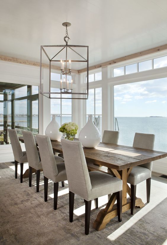 a coastal dining space with a view looks cozier with a rustic dining table