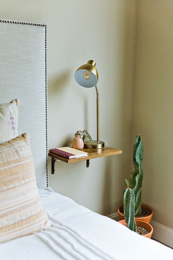 a small wooden nightstand attached to the wall can hold several necessary objects
