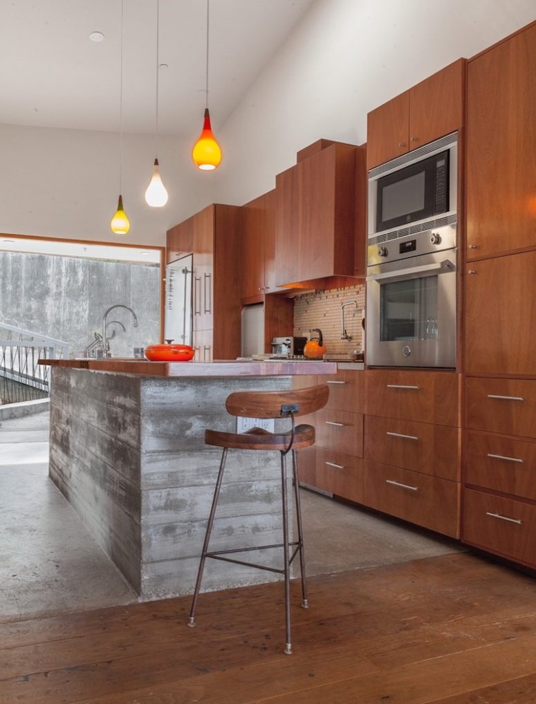 wood kitchen design The kitchen is clad with warm-colored wood and there's a large kitchen island of concrete and wood
