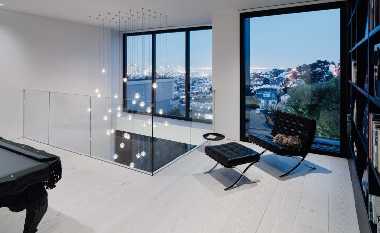 The top floor features a social area with a pool table and bookcases, the furniture is black and it contrasts white surroundings