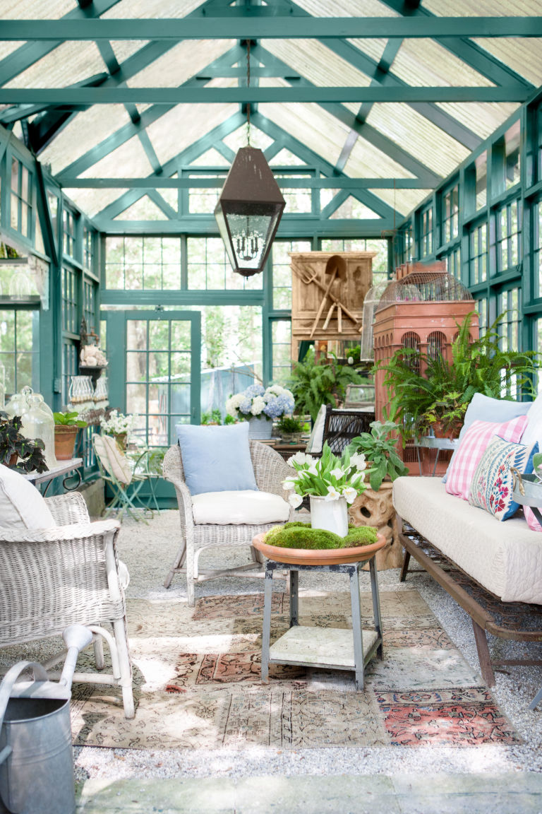 a former greenhouse painted teal became a she shed living room with wicker furniture and lots of plants