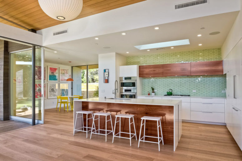 The kitchen is white and with stained wood touches for a cozy feel, I love the green hex tiles that ocver one of the walls