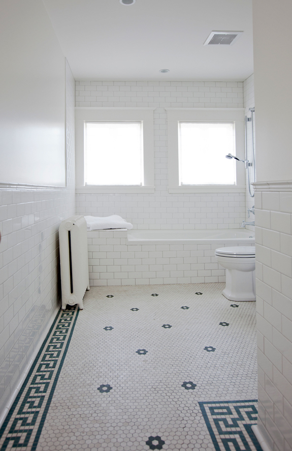 The second bathroom is clad with white subway tiles and hexagon penny ones