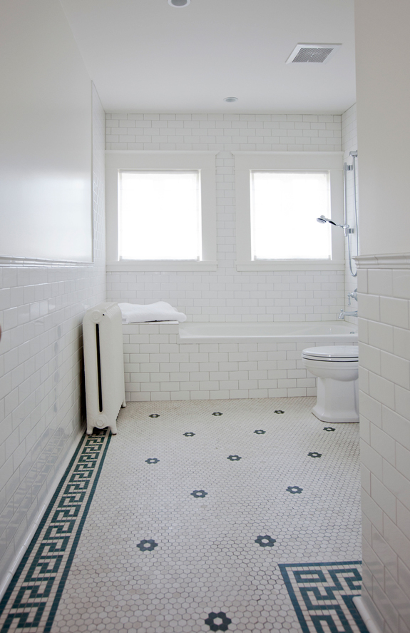 The second bathroom is clad with white subway tiles and hexagon penny ones