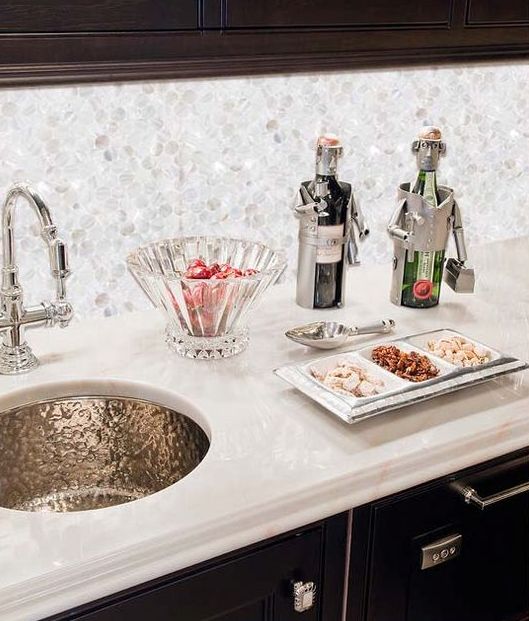 a kitchen backsplash of mother of pearl looks amazing with a marble countertop and a copper sink