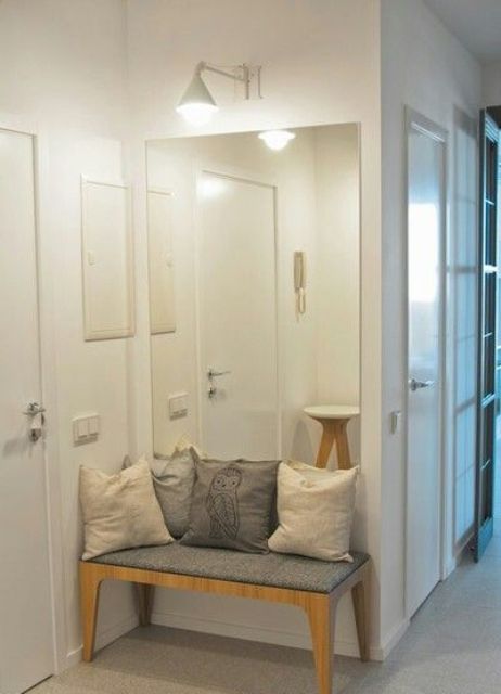 a small entryway needs only a comfy bench and a large mirror to make it look bigger