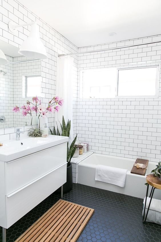 a white bathroom with subway tiles and black hexagon ones on the floor to make it stand out