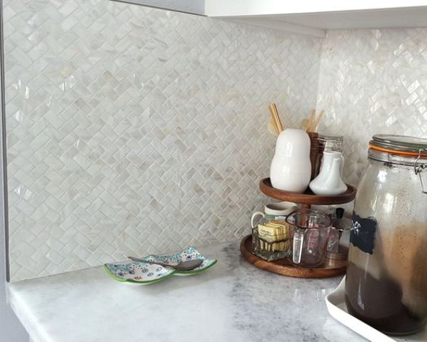 mother of pearl tiles clad in a herringbone pattern for sprucing up a neutral kitchen