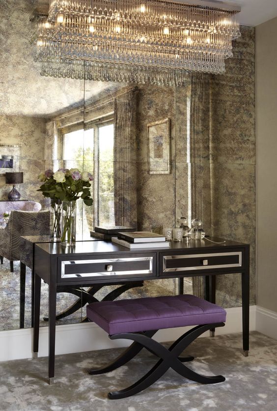a faded mirror wall reflects the light from a large crystal chandelier giving an exquisite touch