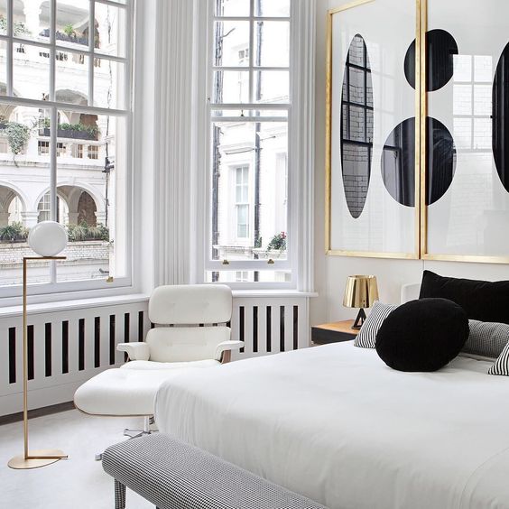 abstract black and white wall art piece in gilded frames add to the white bedroom