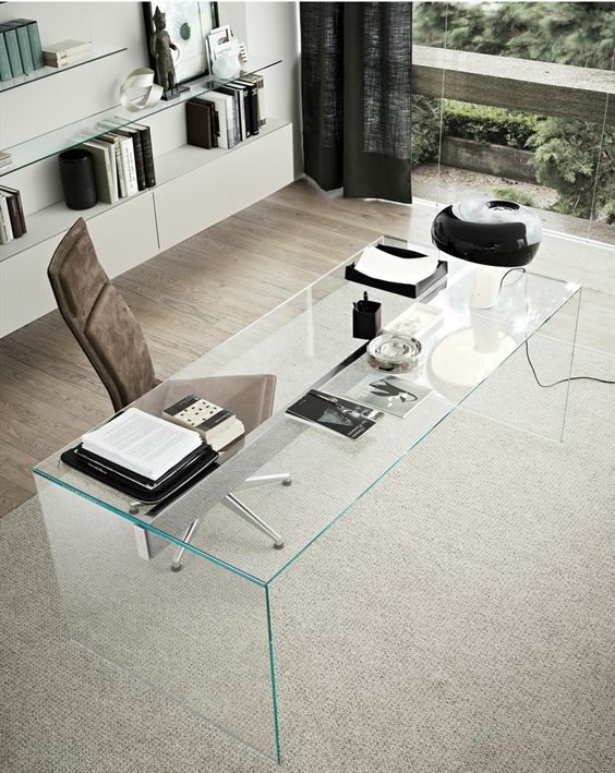 a masculine home office is made cooler with a clear glass desk, it brigns an edgy look