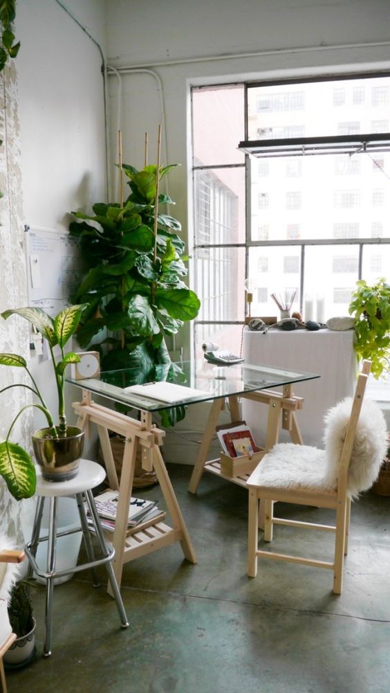 a modern rustic desk with wooden trestle legs and a glass tabletop and additional storage on the legs