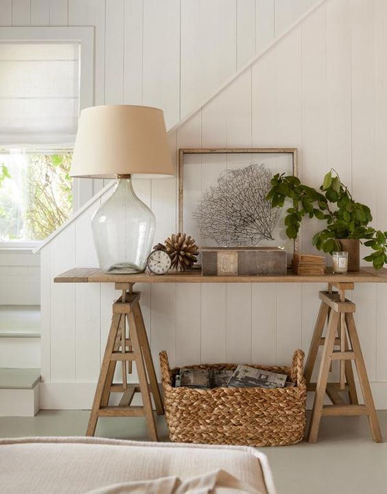a wooden trestle table used in an entryway or living room as a console, a basket for additional storage