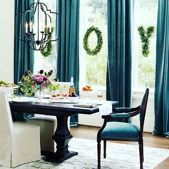 teal velvet curtains and chairs make this dining room refined and gorgeous