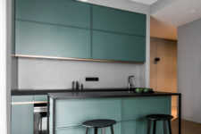 02 The kitchen features sleek green cabinets, a grey backsplash, a kitchen island with black framing and black stools