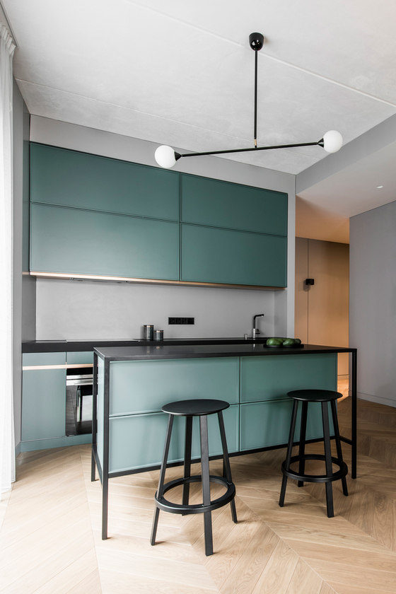The kitchen features sleek green cabinets, a grey backsplash, a kitchen island with black framing and black stools